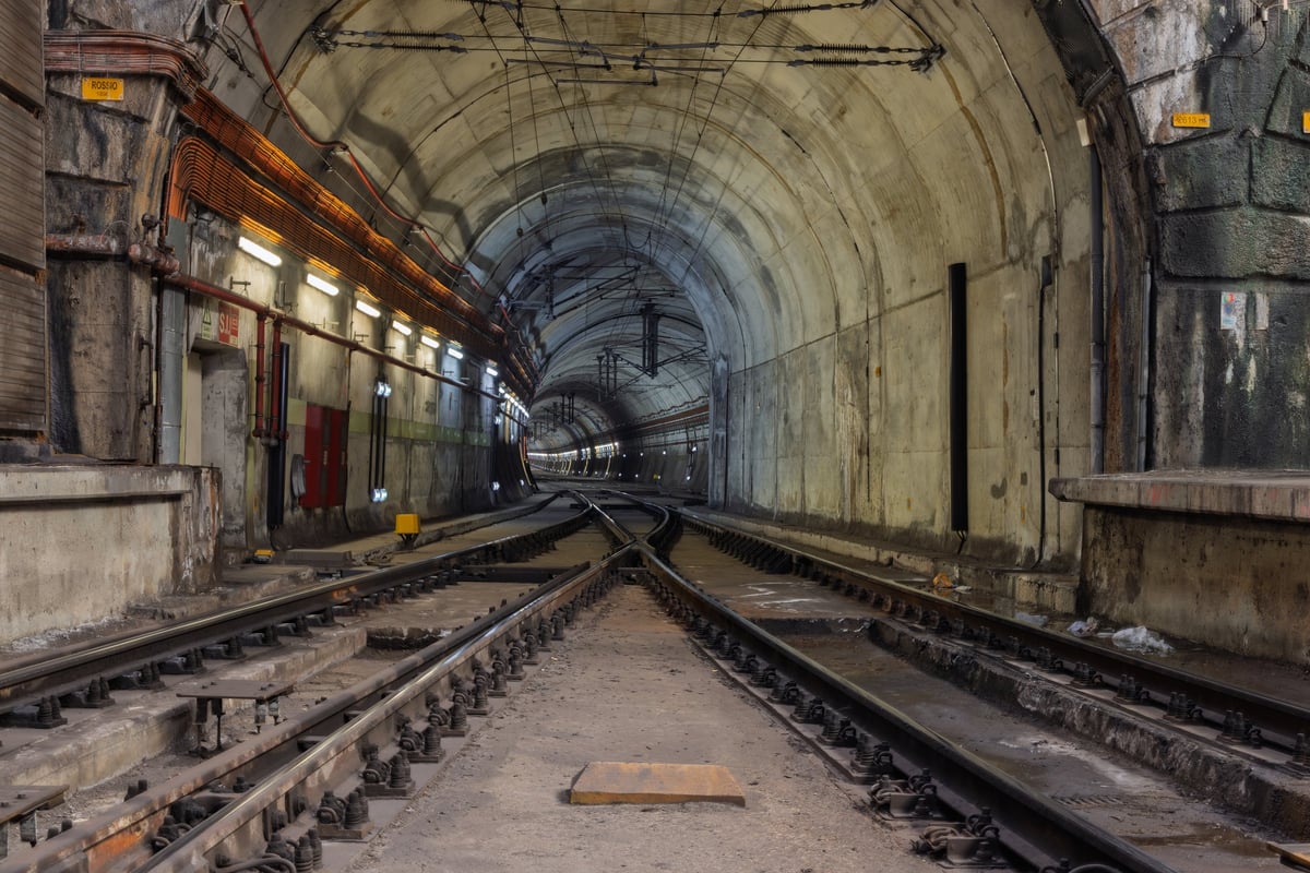 Intersecting train tracks inside illuminated tunnel